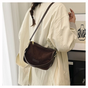 Side view of dark brown suede saddle bag with adjustable strap on a minimalist model