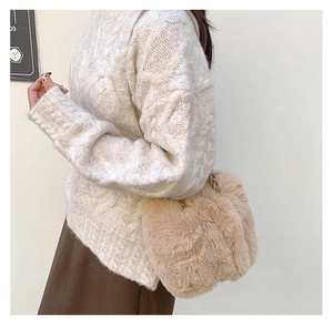 Detail of plush faux fur handbag with woven handle on model in autumn outfit