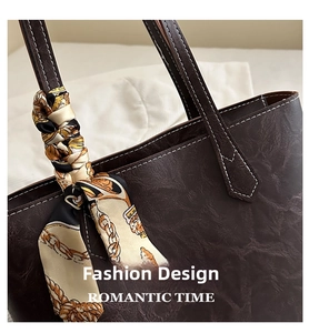 Detail of dark coffee tote bag featuring white contrast stitching and a silk-like scarf