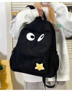 Detailed shot of black corduroy backpack with cartoon eyes and yellow star plush charm