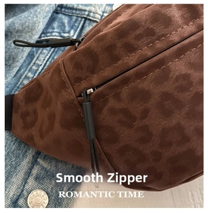 Detail of smooth leopard print crossbody bag with black puller and zipper on denim