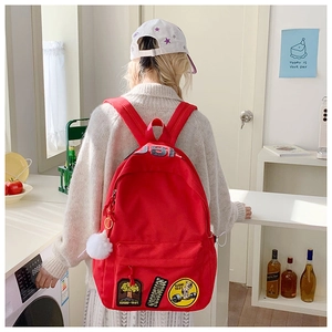 Close-up of red canvas backpack with USA embroidery and creative patches on the back