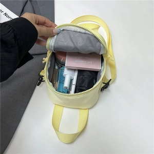 Cute yellow canvas mini crossbody bag showing internal space for makeup and umbrella