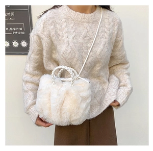 Detail view of cream faux fur cloud bag featuring woven handles and crossbody strap