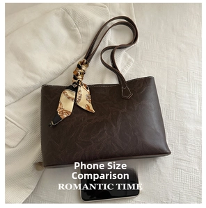 Deep brown tote bag detail with silk scarf handle and mobile phone for size reference