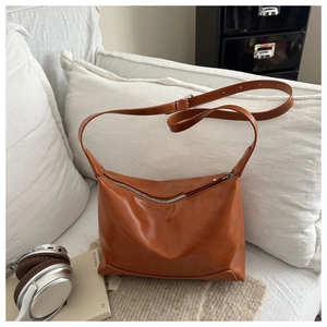 Detailed close-up of a brown vintage leather shoulder bag with zipper and soft texture