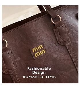 Detailed view of the dark brown leather tote bag showing fine stitching and gold logo