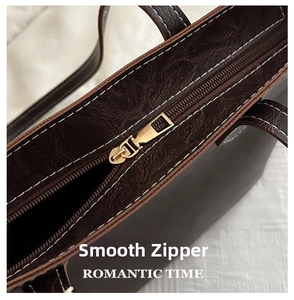 Close-up of polished dark brown tote bag with white stitching and golden metal zipper