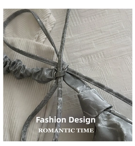 Close-up of metallic silver pleated bag showing adjustable shoulder strap knot detail