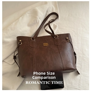 Detailed view of dark brown tote bag featuring vintage leather texture and gold logo