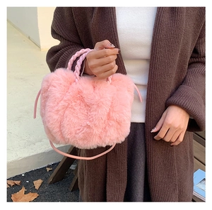 Close-up of pink plush pleated cloud bag with woven handles and furry texture