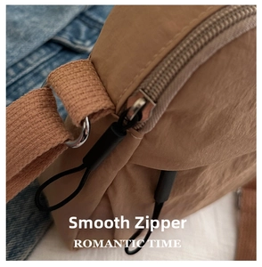 Detail of khaki nylon bag featuring a smooth black zipper and silver D-ring metal buckle