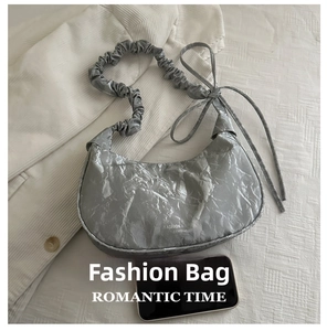 Silver hobo bag detail with metallic texture and drawstring next to a mobile phone