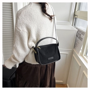 Detail of a black frosted matte shoulder bag featuring elegant gold metal hardware