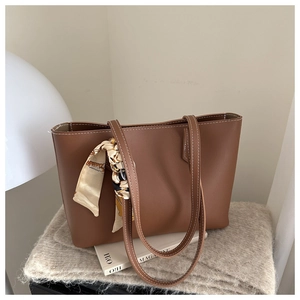 Close-up of brown faux leather tote bag texture with fine stitching and silk scarf detail