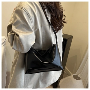 Close-up of a large black vintage leather tote bag worn by a model in a cozy interior