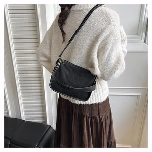 Detail of minimalist black crossbody bag with matte texture and gold hardware accents
