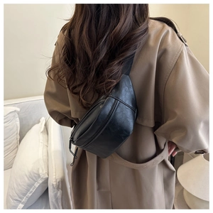 Back view of a large black PU leather crossbody waist bag on a khaki trench coat