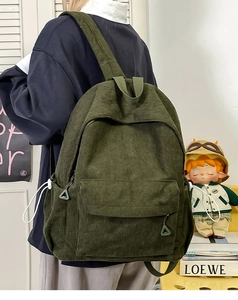 Side view of dark green corduroy backpack showing vertical texture and side drawstrings
