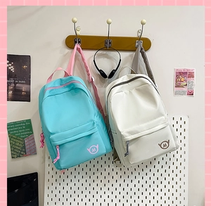 Detail of color-block nylon backpacks in blue and beige with round wing logo