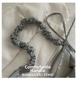 Close-up of drawstring handle on silver nylon cloud bag with soft ruched fabric texture