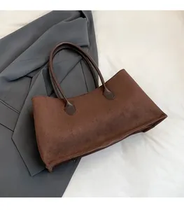 Detail showing the vintage matte suede texture and shoulder strap of a brown tote bag