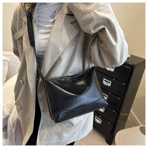 Detail of minimalist black faux leather tote with adjustable strap and zip closure