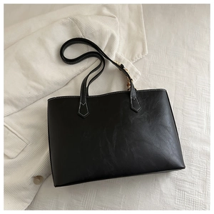 Gros plan sur un sac cabas noir avec texture litchi et détails de surpiqûres blanches