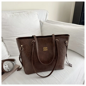 Macro shot of vintage dark brown pebbled leather texture and gold logo on tote bag