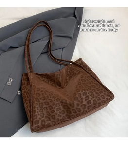 Detail of leopard print tote bag texture and slim shoulder straps on a grey blazer