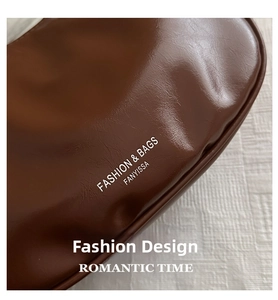Close-up of brown leather bag corner with pleated texture and white fashion logo text