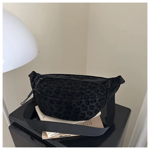 Detail of a black leopard print chest bag with dual zippers and adjustable wide strap