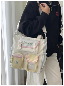 Detail of color-block nylon tote bag showing multiple functional front pockets with branding