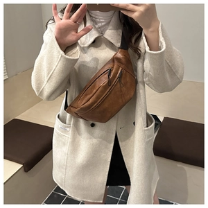 Close-up of retro brown PU leather chest bag with zipper detail on white coat