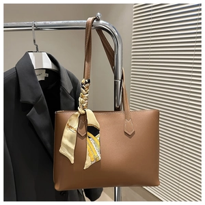 Close-up of brown leather tote bag with silk scarf detail hanging on a rack