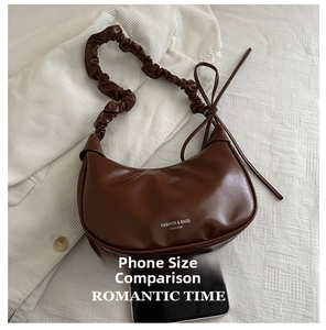 Close-up of brown textured leather crescent bag with drawstring and size phone comparison
