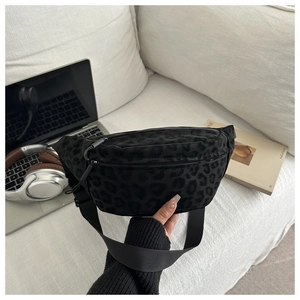 Detail of black leopard print waist bag with adjustable strap on a minimalist sofa