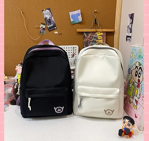 Detail of black and beige nylon backpacks with signature M logo in a dorm setting