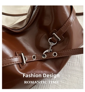 Detail of vintage brown glossy underarm bag showing silver zipper and metallic eyelet strap