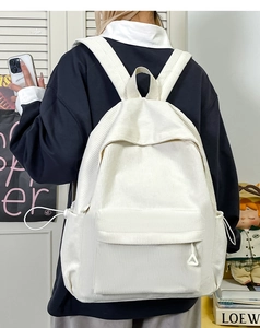 Detail view of corduroy backpack showing drawstring side pockets and fine ribbed texture
