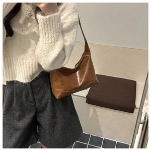 Brown soft leather tote bag worn as an underarm shoulder bag for commuting style