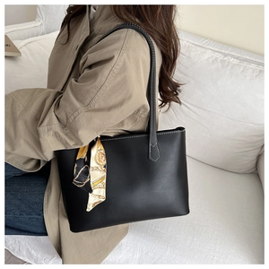 Detail of black leather tote bag with white contrast stitching and printed silk scarf