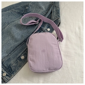 Close-up of a purple water-resistant oxford fabric crossbody bag on denim background