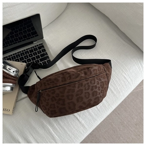 Detailed view of leopard print suede belt bag with adjustable strap on a sofa