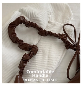Detail of the brown oil-wax leather shoulder bag featuring a pleated handle and bow knot
