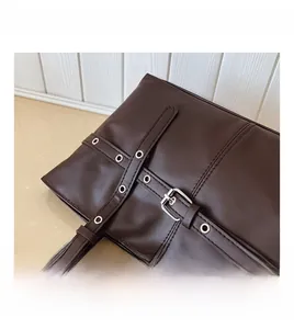 Detailed macro view of dark brown wax leather tote with silver metal eyelets and stitching