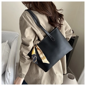 Detail of black pebbled tote bag with elegant printed silk scarf on the handle