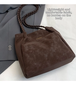 Detail view of large dark brown suede tote bag with woven handles and brand lettering