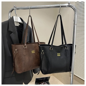 Detail of vintage matte leather tote bags in dark brown and black with gold logo