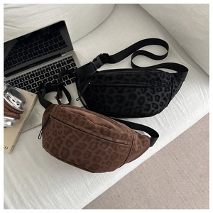 Detail of leopard print chest bags in black and brown on a white textured sofa